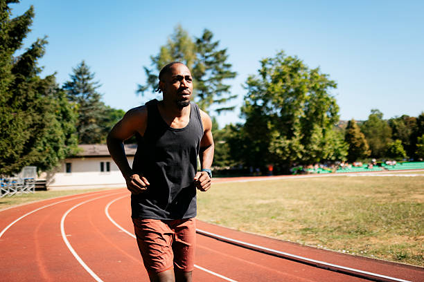 Determined athlete running on track in stadium, focused on his training