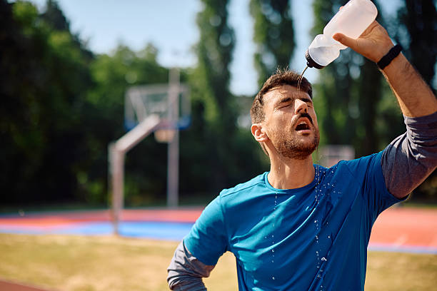istock Athletic man refreshing himself with fresh water while working out outdoors. 2223272099