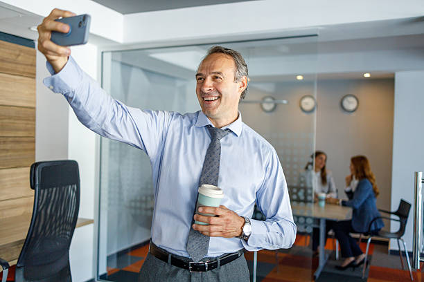 istock Businessman taking a selfie in the office while holding a coffee 2223273379
