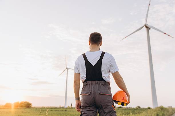 istock Engineer looking at wind turbines in a field at sunset 2223273480
