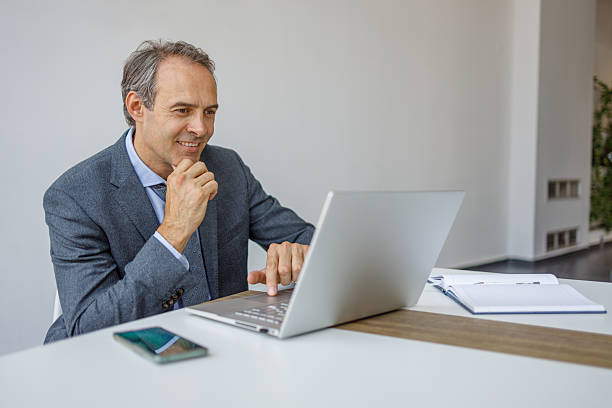 istock Smiling businessman working on laptop in modern office 2223273939