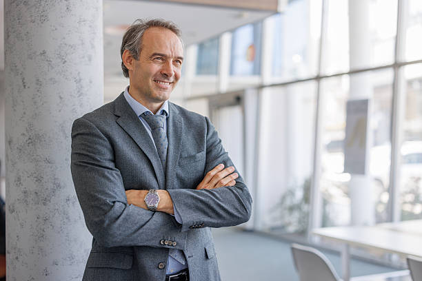 istock Smiling businessman leaning against pillar in office hallway 2223274484