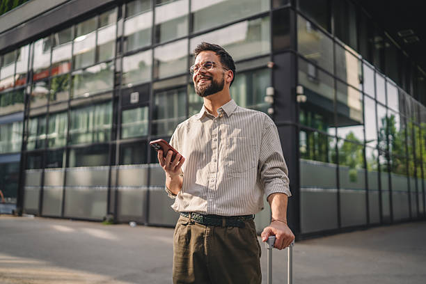 istock one man with beard and eyeglasses walk with suitcase and use phone 2223275536