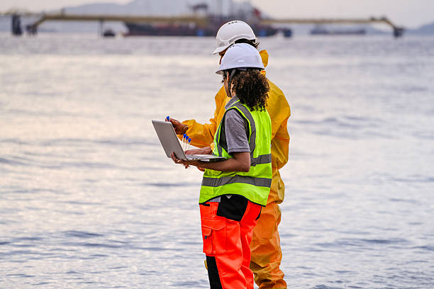 istock Two field scientists in PPE gear analyzing seawater samples using test tubes and a laptop. Environmental monitoring and pollution control on the coastline are depicted. 2223286775