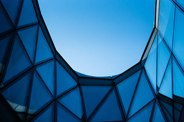Contemporary architecture building with glass and metal facade on clear blue sky. For illustrating urban design or modern construction concepts. Copy space for text