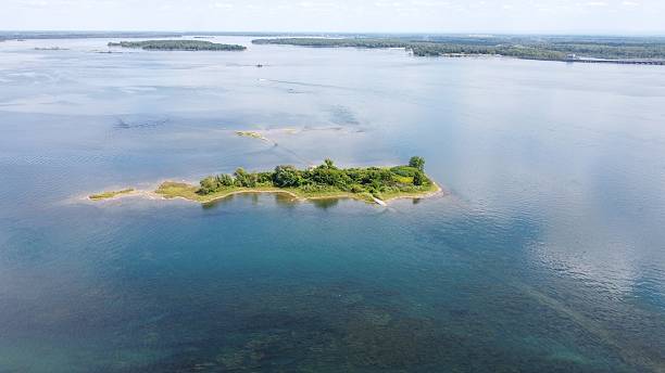 Small Green Island Surrounded by Blue Water and Blue Sky with White Clouds