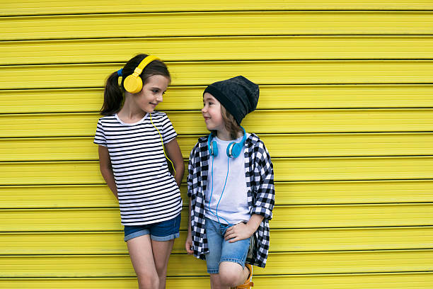 Happy boy and girl enjoying a fun day together, dressed in stripes and plaid, with headphones  Personality, character, independence, young spirit