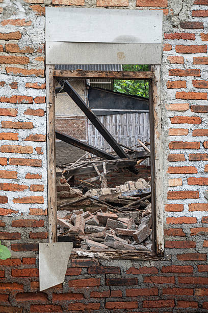 Window frame of a collapsed house without shutters, revealing scattered bricks and wood debris inside. Ideal for urban decay themes, disaster visuals, or historical documentation