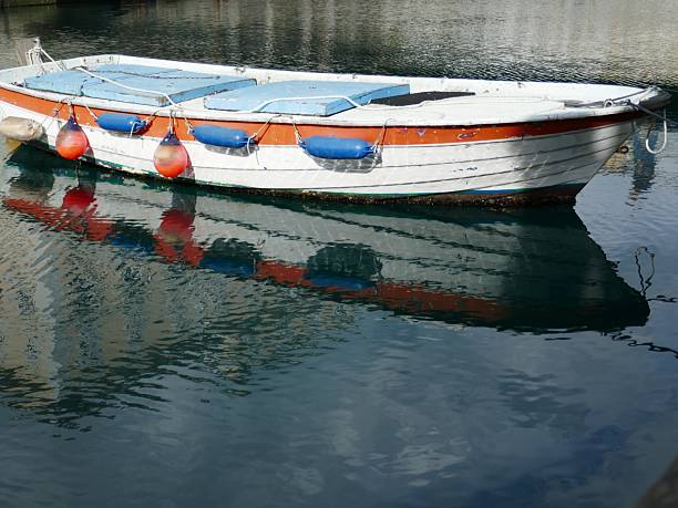 istock Colorful old boat floating on water with reflection and hanging docking bumpers 2223303753