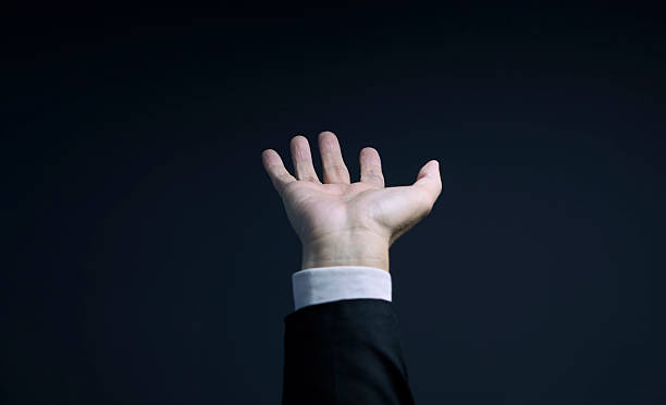 istock Businessman reaching out with open hand on dark background 2223307517