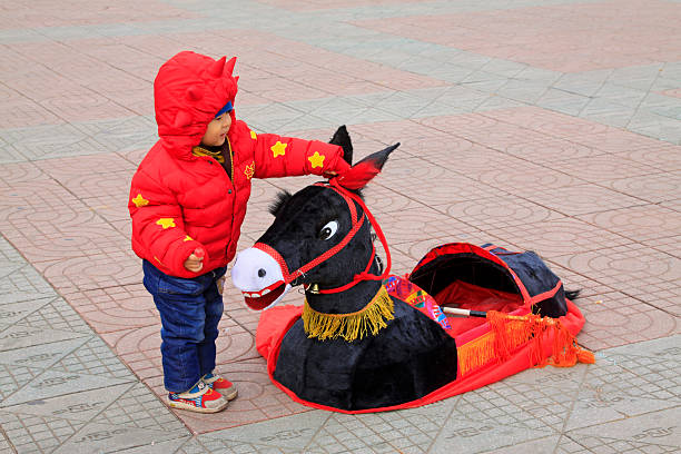 LUANNAN COUNTY - FEBRUARY 27: A child playing with the donkey props in the square, on February 27, 2015, Luannan County, Hebei province, China