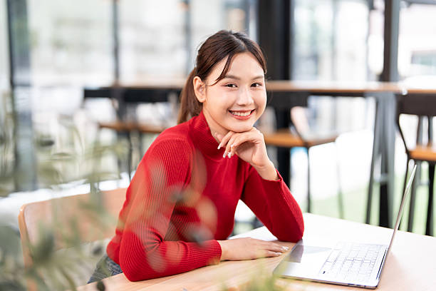 istock Young beautiful joyful woman in red sweater smiling while working with laptop 2223312039