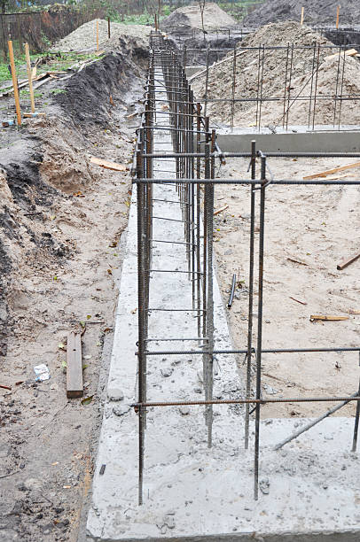 istock Strip foundation construction close up. House concrete foundation with reinforced footing trenches, rebars installed and concrete poured. 2223318231