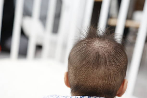 A close-up photo of the back of a baby's head with thinning hair.