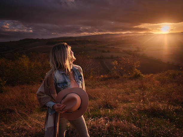 Young happy woman with a hat enjoying in autumn day on a hill at sunset. Copy space. Photographed in medium format.