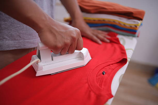 Close Up Of Man Hands Ironing Shirt On Ironing Board With Steaming White Iron