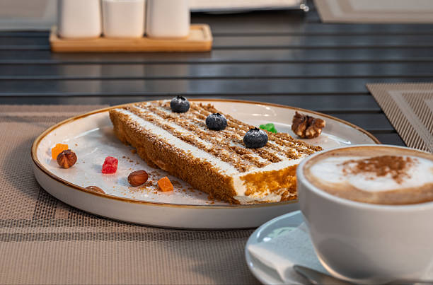 istock A piece of honey cake on a plate on a table in a sidewalk cafe. 2223325401