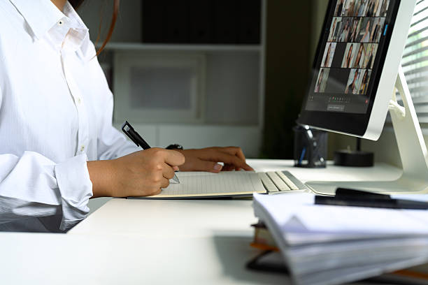 istock Close up of woman taking notes while attending a virtual meeting on her desktop computer 2223327182