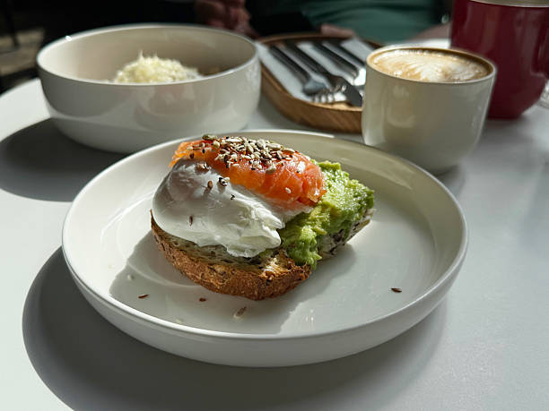 istock Gourmet Open-Faced Sandwich: Avocado, Poached Egg, and Smoked Salmon. Dining Out Breakfast Idea. Hand-Taken Smartphone Photo, Selective Focus, Bright Sunlight, No AI 2223327228