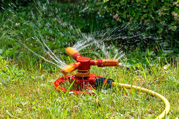 Close-up of automatic lawn watering. Water drops fall on green lawn grass.