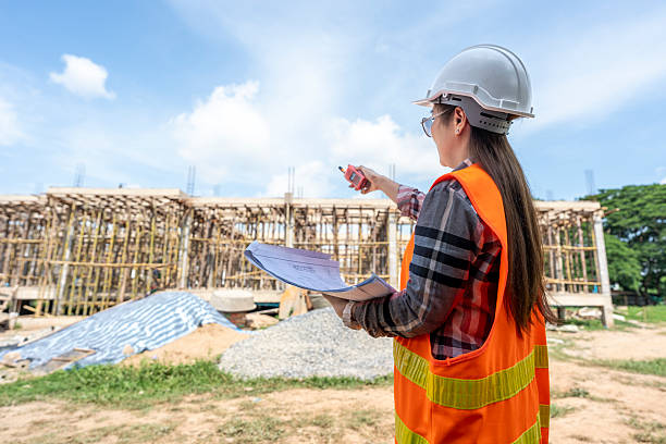istock Female Engineer Supervising Construction Site with Blueprints and Walkie-Talkie 2223331625