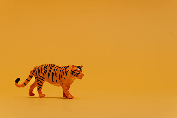 Small toy tiger stands against a bright orange backdrop, symbolizing unexpected hazards in child safety education