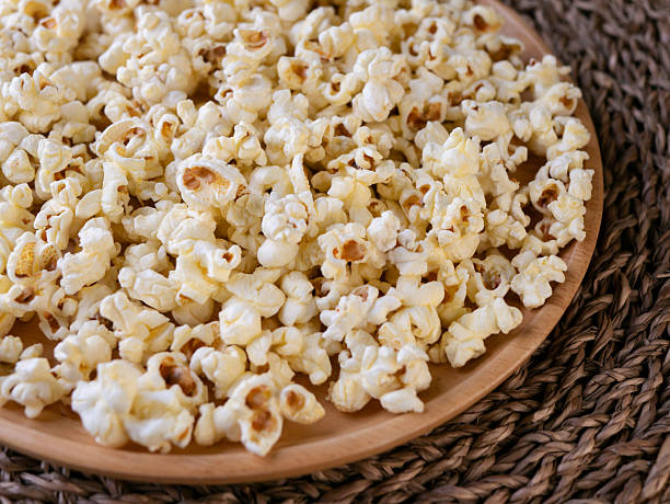 Sweet caramel popcorn in a bowl on a wooden background. Salted caramel popcorn. Caramel sauce. Close up. Topping. Place for text. Copy space