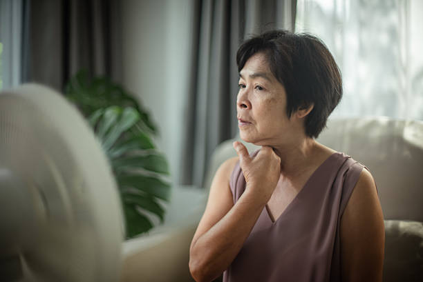 istock Mature woman experiencing hot flash while sitting on sofa. 2223337411