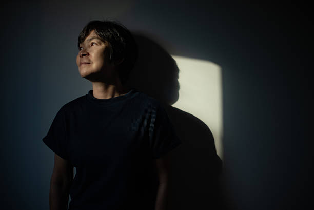 Asian mature woman enjoying sunlight at home.