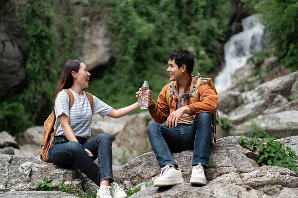 Outdoor Adventure. Young hikers sharing water during a mountain trek.