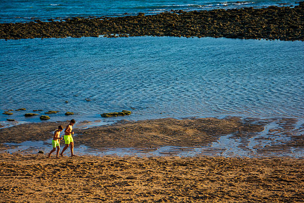 People stroll along a rocky beach in Turkey during autumn, enjoying the peaceful seaside atmosphere and cooler weather. A perfect off-season getaway.