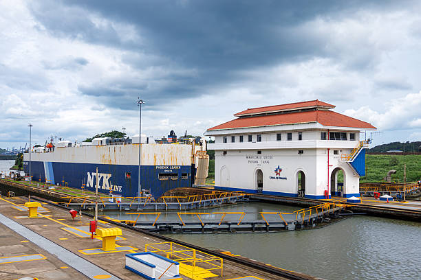 Panama City, Panama - June 12, 2025: A ship leaves the Miraflores Lock. Building exterior of the control center in the Panama Canal.