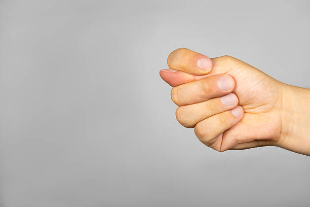 istock On a gray background, a man's hand with fingers folded in a fig sign 2223350348