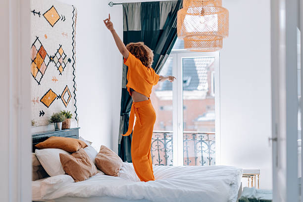 istock Joyful woman dancing on cozy bed in bright room 2223350594