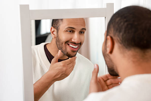 istock Smiling man looking at mirror at home 2223351194