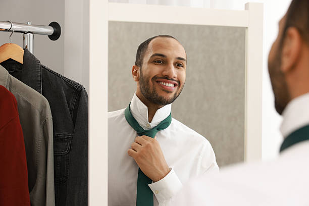 istock Smiling man adjusting necktie near mirror at home 2223351196