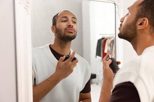 istock Handsome man spraying perfume near mirror at home 2223351217