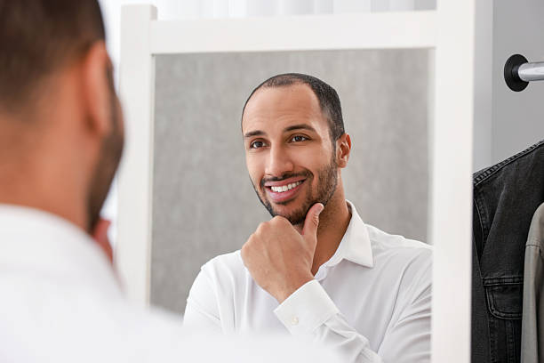 istock Smiling man looking at mirror at home 2223351297