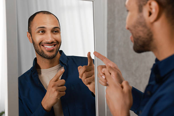 istock Smiling man looking at mirror at home 2223351298