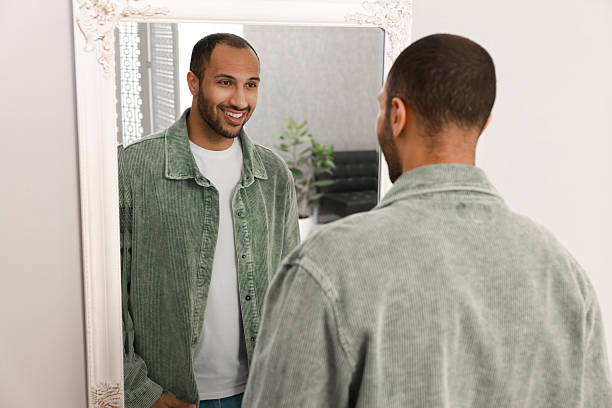 istock Smiling man looking at mirror at home, back view 2223351302