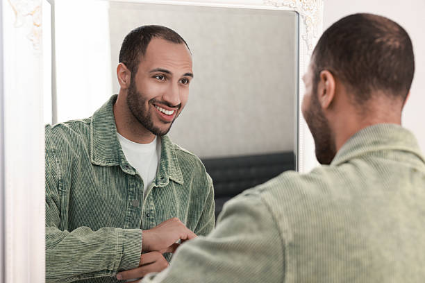 istock Smiling man dressing near mirror at home 2223351329