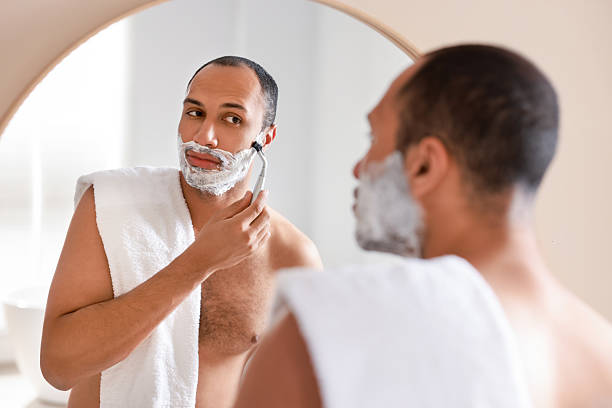 istock Handsome man shaving with razor near mirror in bathroom 2223351386