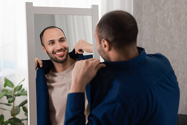 istock Smiling man looking at mirror at home 2223351390