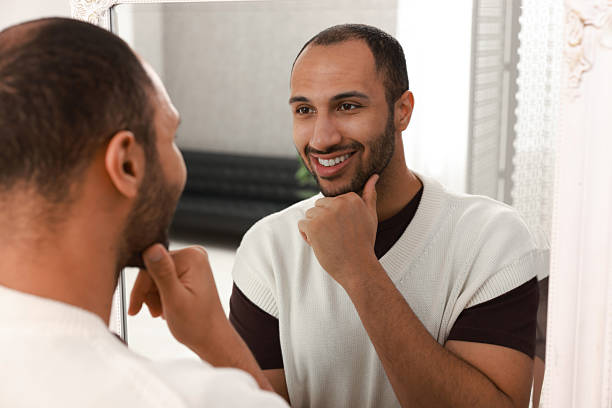istock Smiling man looking at mirror at home 2223351428