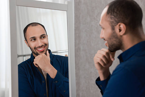 istock Smiling man looking at mirror at home 2223351435