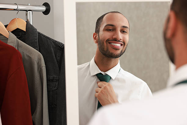 istock Smiling man adjusting necktie near mirror at home 2223351440