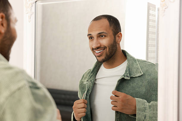 istock Smiling man dressing near mirror at home 2223351472