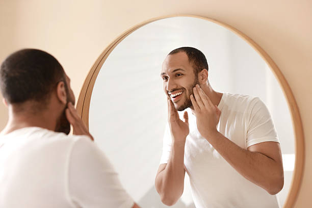 istock Smiling man looking at mirror in bathroom 2223351519