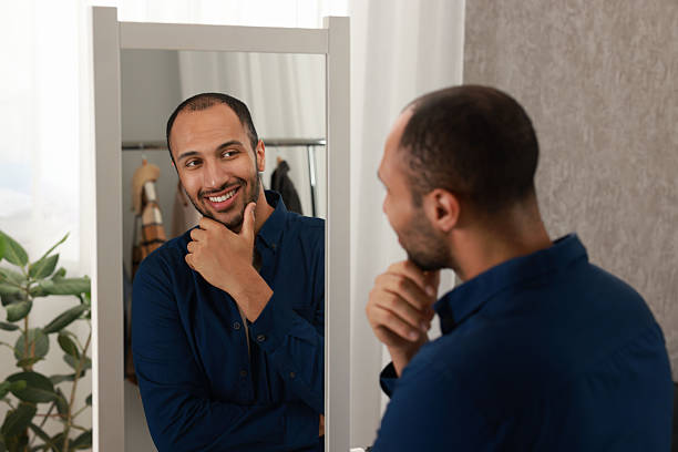 istock Smiling man looking at mirror at home 2223351522