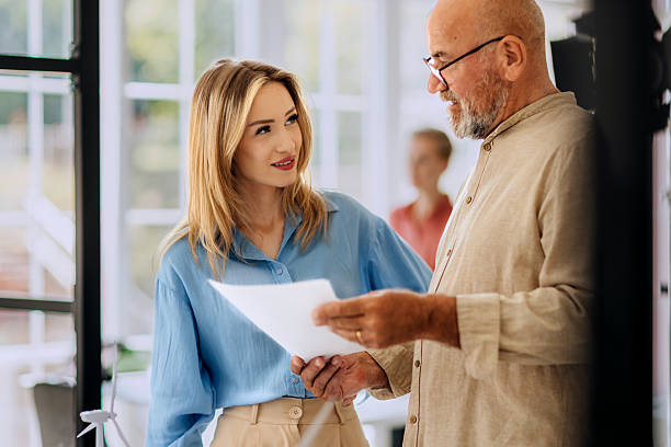 istock Senior man talking with female colleague in office 2223352109
